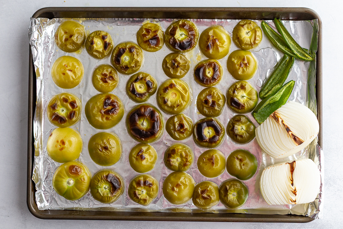 tomatillos, peppers and onion on a baking tray after being roasted