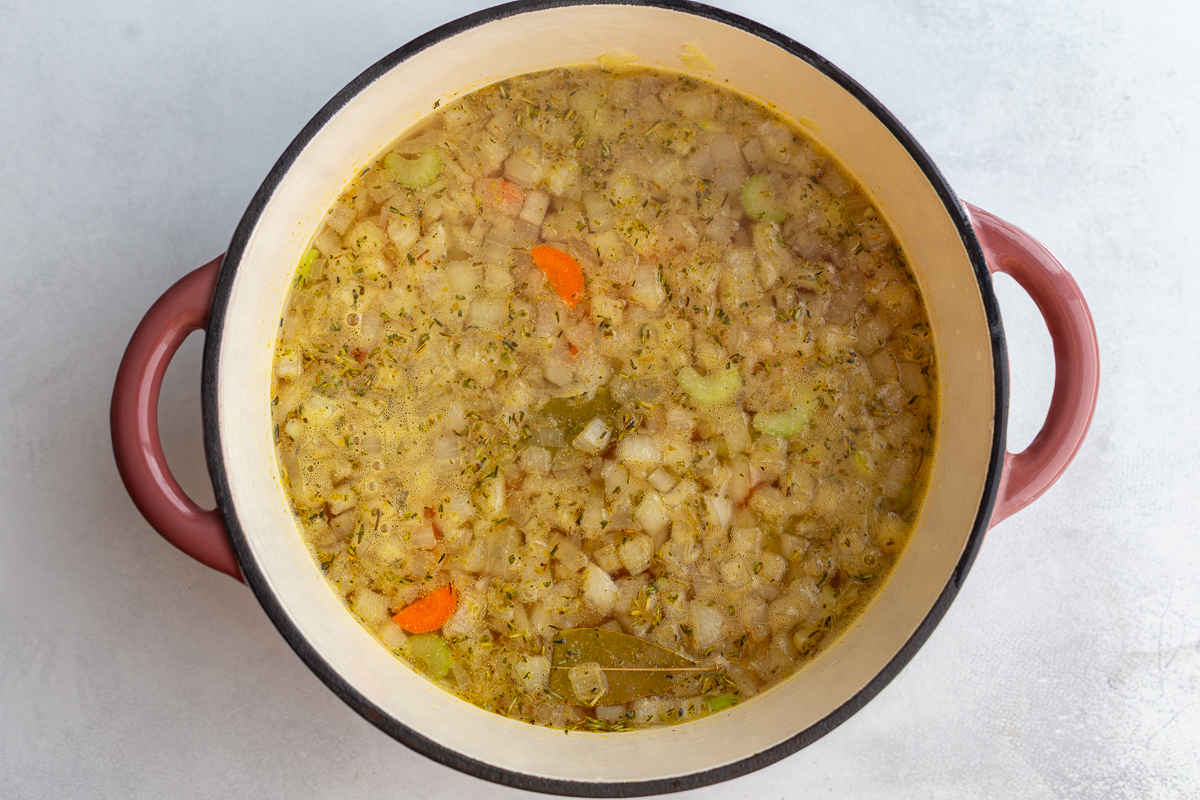 onion, celery, and carrot pieces in a large pot of broth