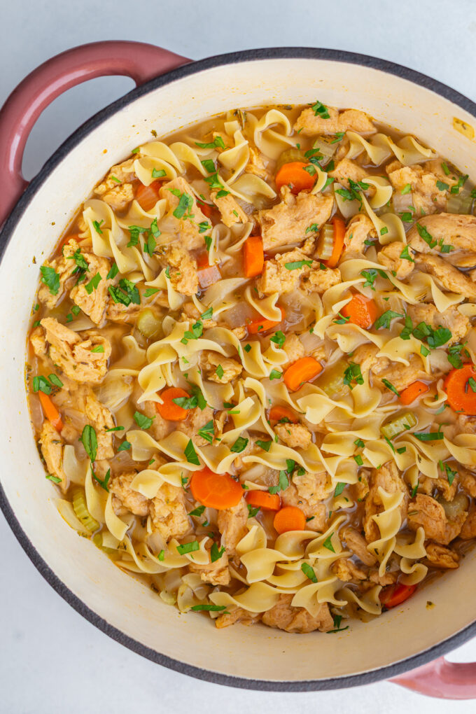 large soup pot of vegetarian chicken noodle soup topped with fresh parsley