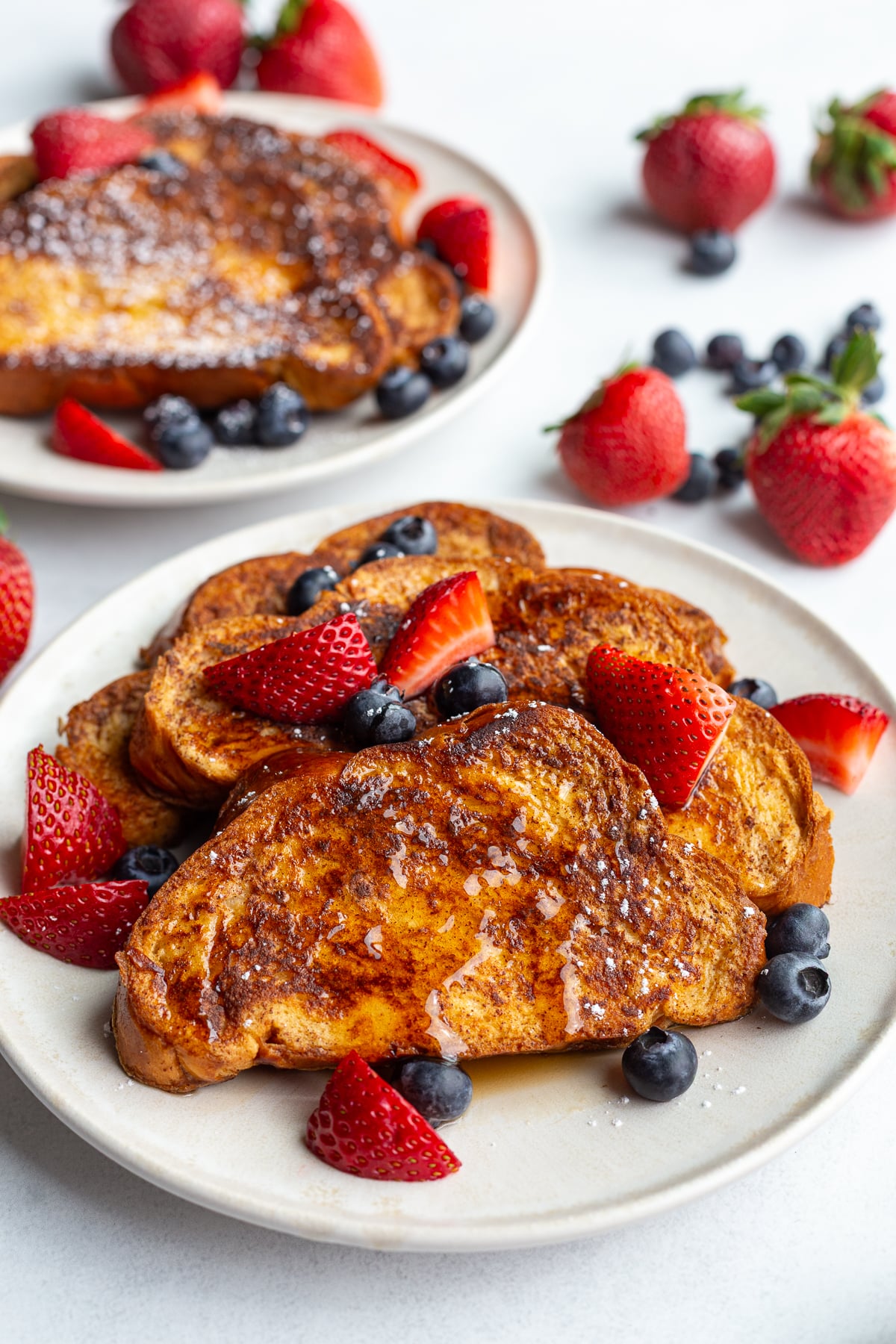 french toast on a plate with fresh strawberries and blueberries