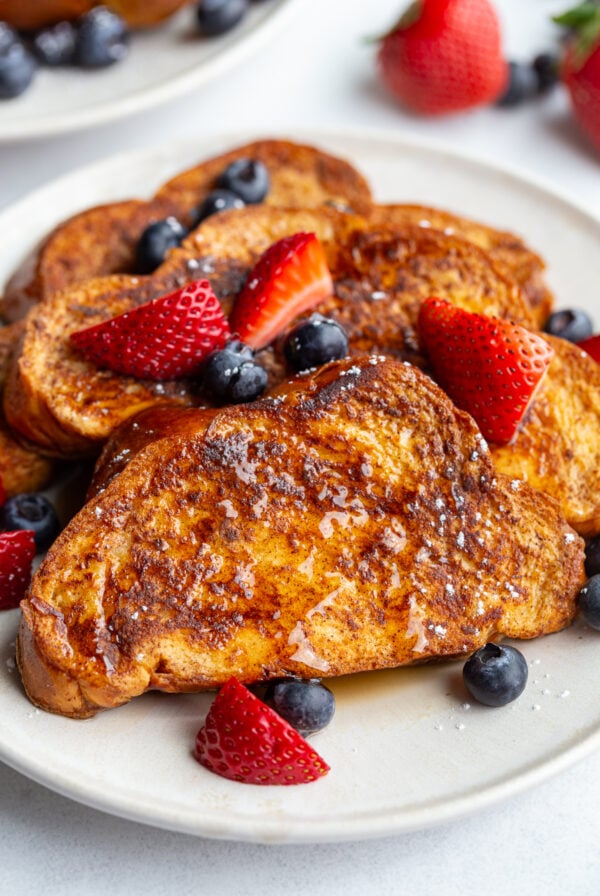 french toast on a plate with fresh strawberries and blueberries