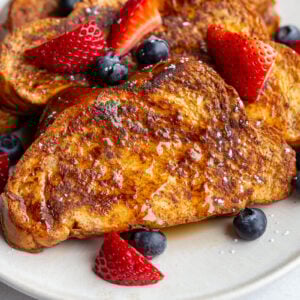 french toast on a plate with fresh strawberries and blueberries