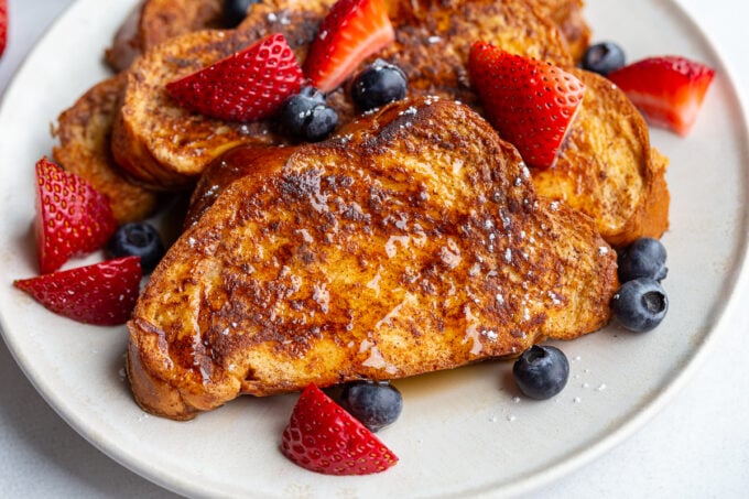 french toast on a plate with fresh strawberries and blueberries