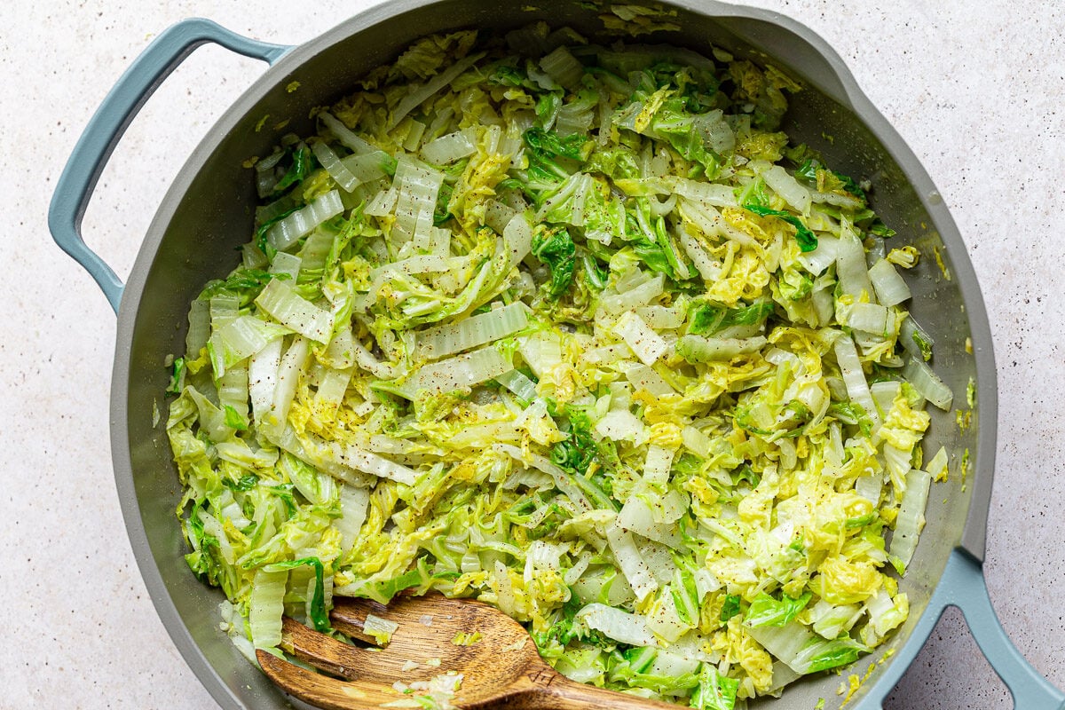 Saut&eacute;ed Napa cabbage in a large skillet.