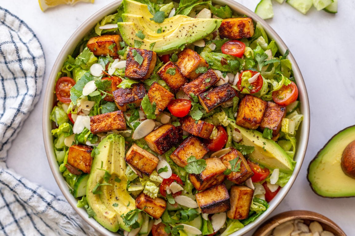 tofu salad topped with sliced avocado and cherry tomatoes
