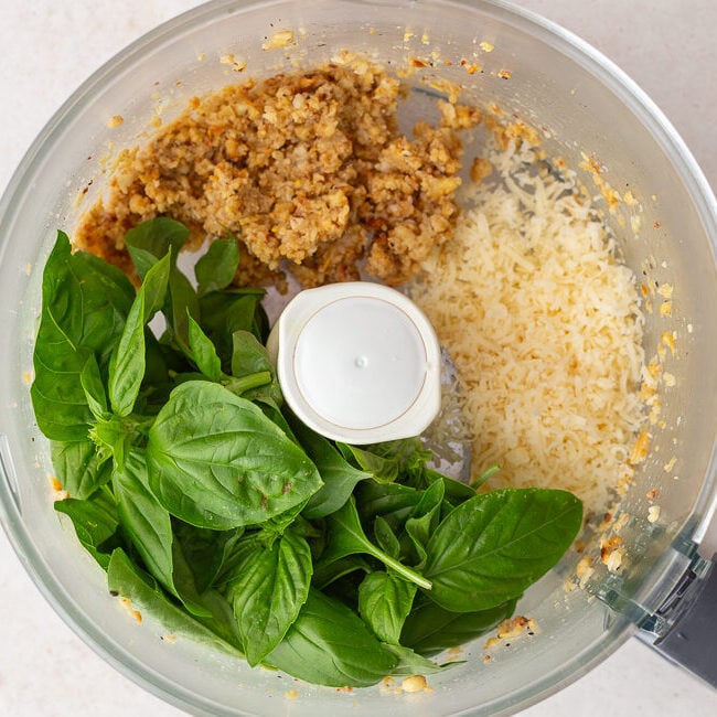 how to make pesto step 2: food processor that has processed pinenutes in it along with fresh basil and Parmesan cheese