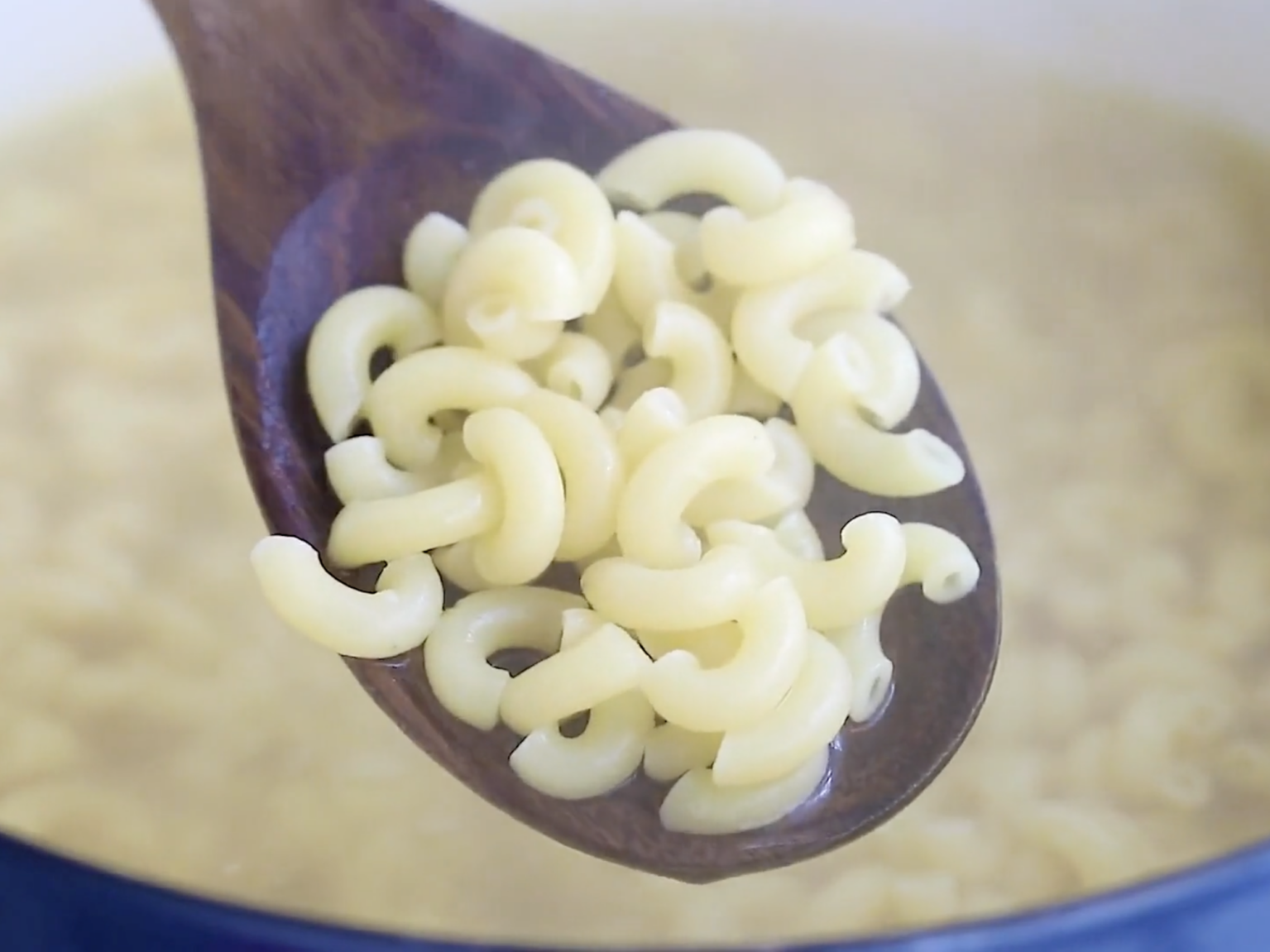 cooked macaroni pasta on a wooden spoon