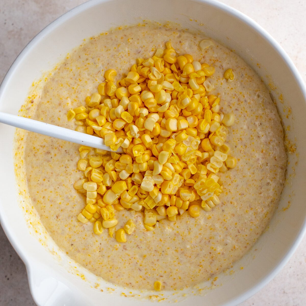 cornbread batter in a large bowl with fresh corn on top