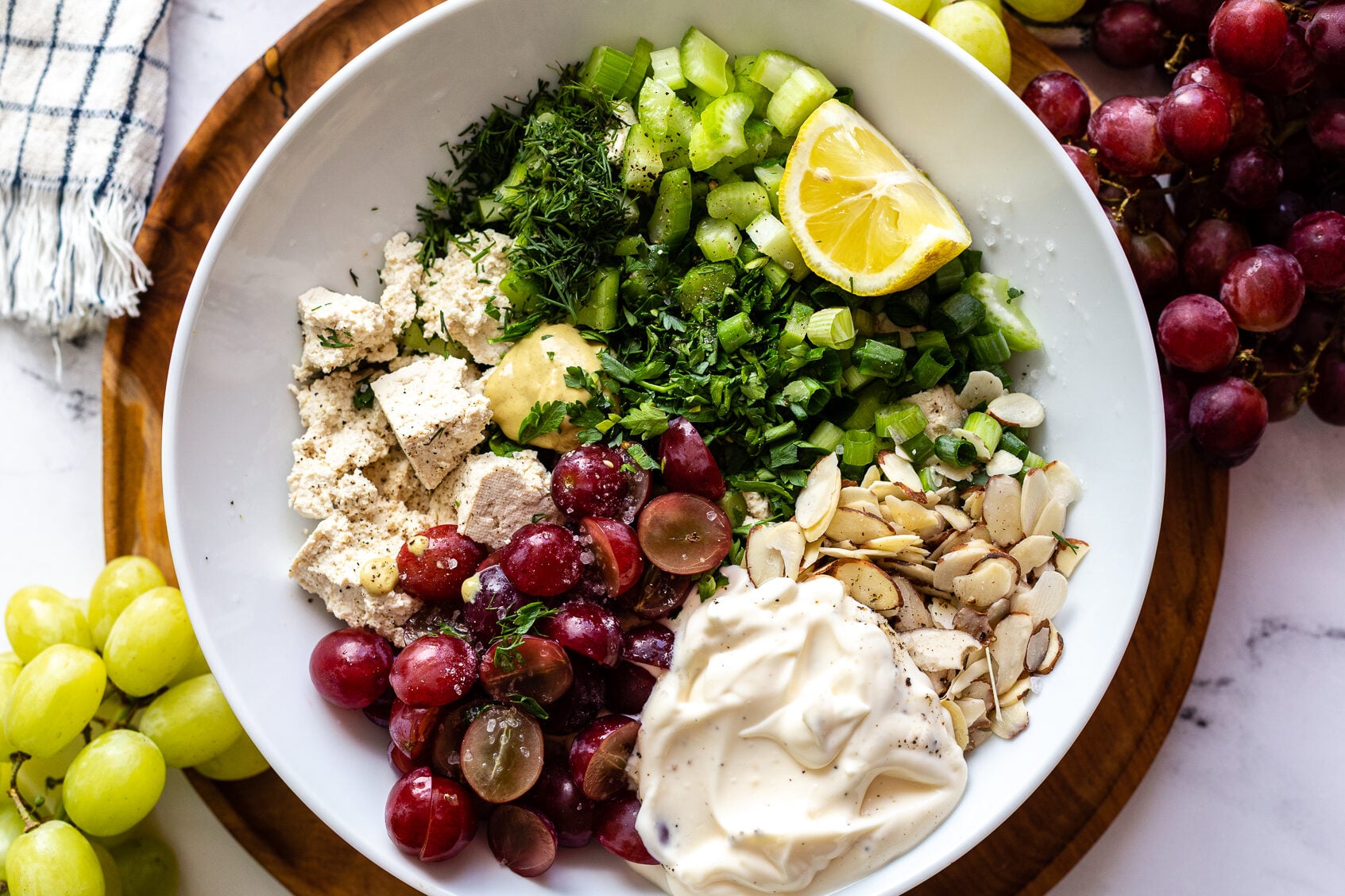 white bowl filled with "vegan chicken salad" that has chunks of tofu, veggies and grapes in it