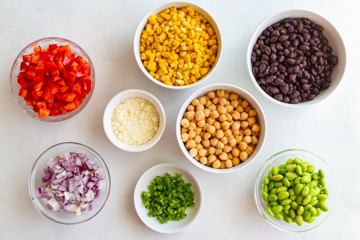 ingredients needed for street corn dense bean salad including beans, edamame, jalapeno, bell pepper, onion and cotija