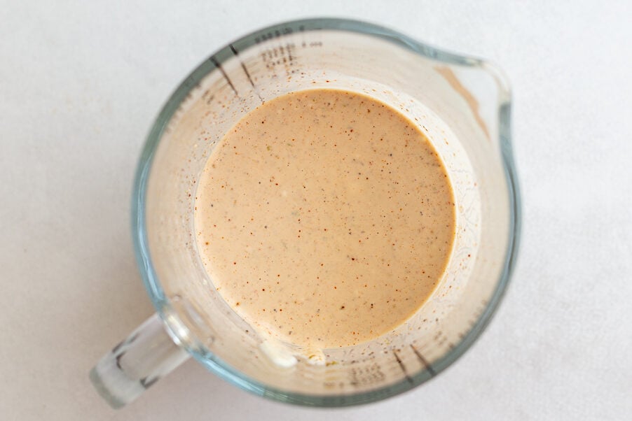 creamy street corn dressing in a measuring cup