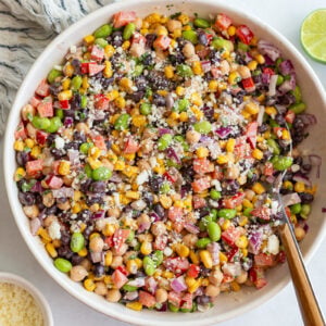 mexican street corn dense bean salad in a large bowl filled with chickpeas, pinto beans, edamame, and fresh veggies topped with cotija