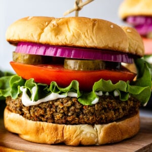 veggie burgers on a sesame seed bun with lettuce, tomato, pickles ,and red onion on it