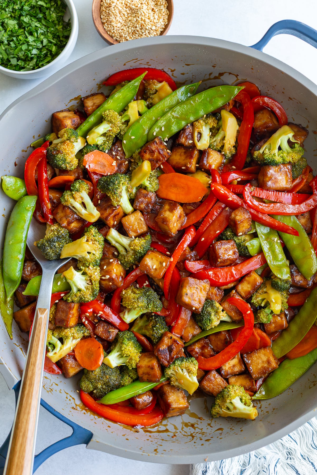 tofu stir fry in a large skillet with sesame seeds sprinkled on top