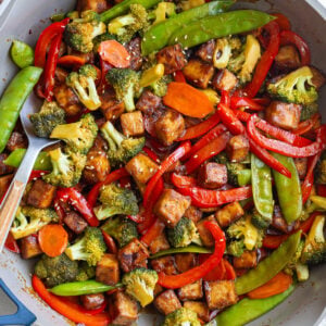 tofu stir fry in a large skillet with sesame seeds sprinkled on top