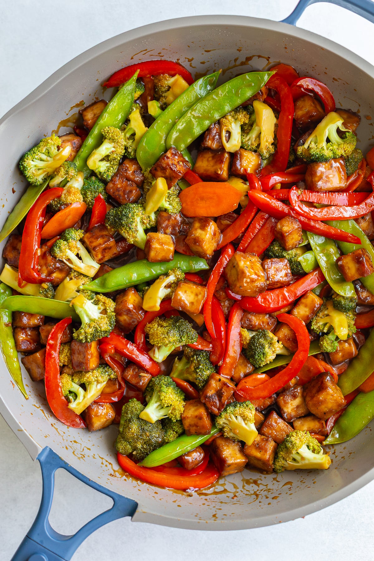 tofu stir fry in a large skillet with sesame seeds sprinkled on top
