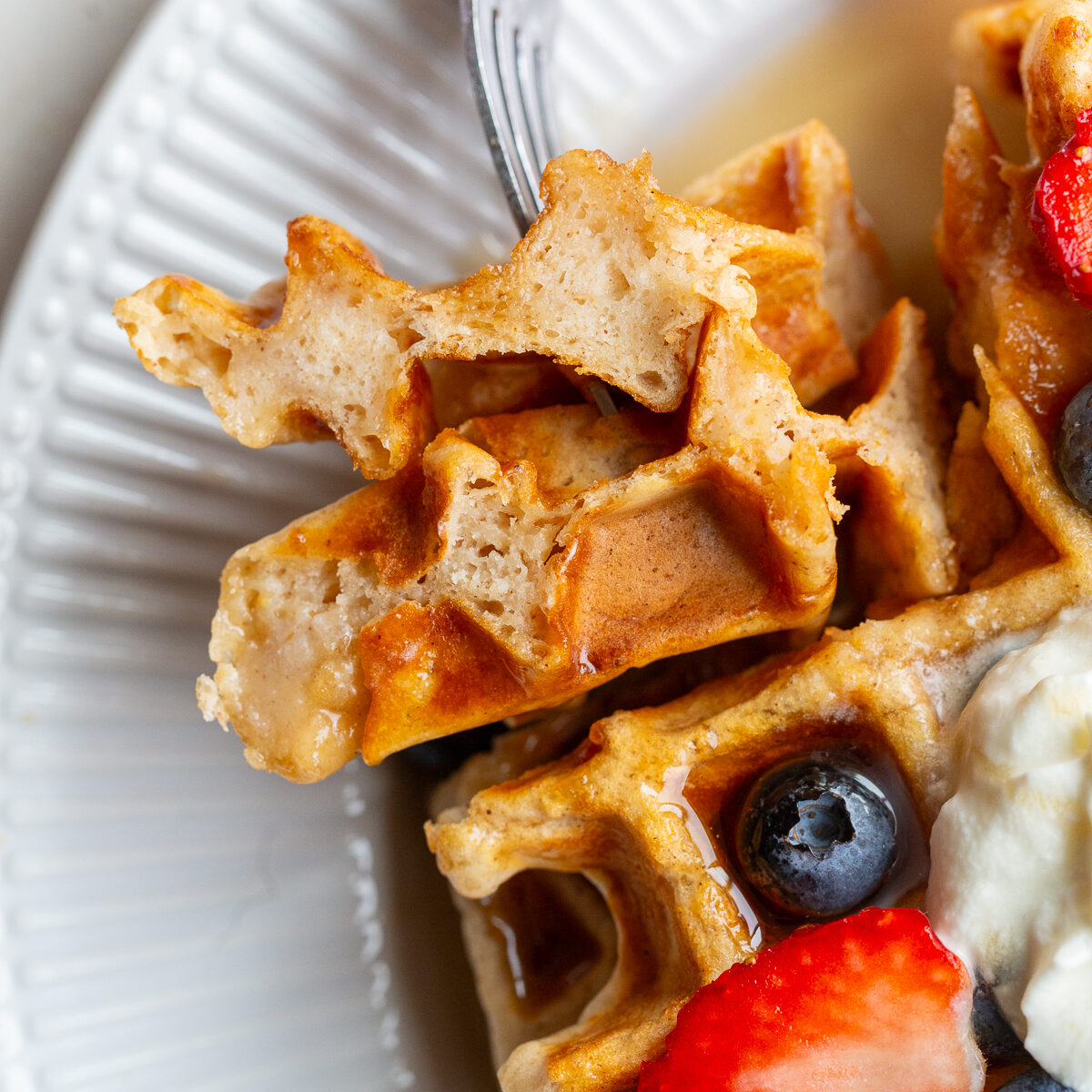 Vegan waffle on a fork with berries.