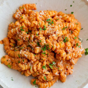 creamy tomato protein pasta in a pasta bowl and topped with herbs