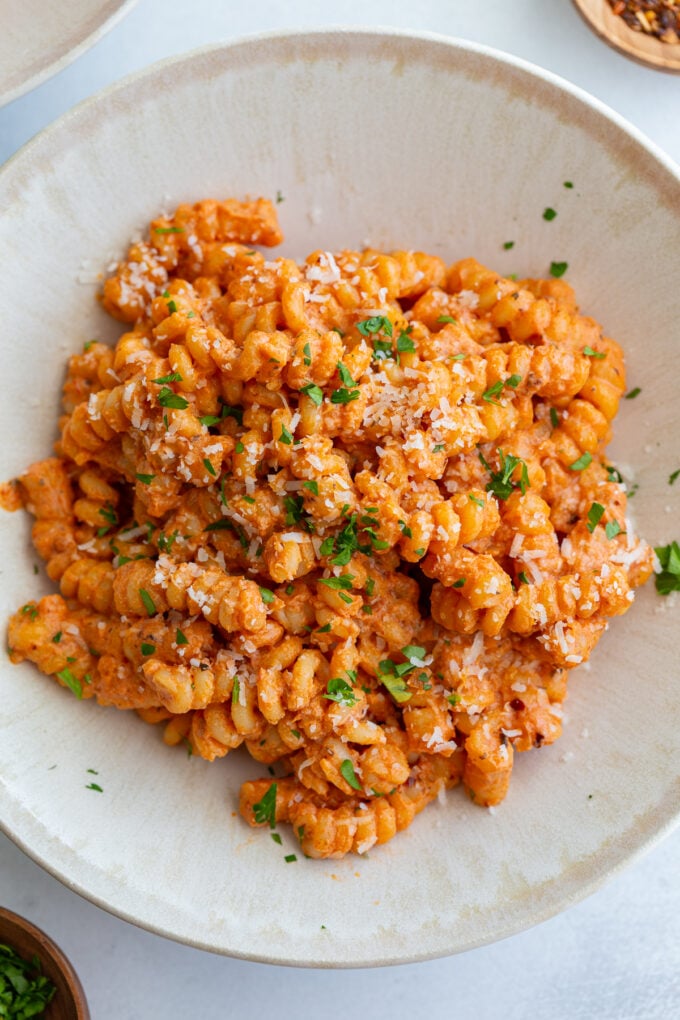 creamy tomato protein pasta in a pasta bowl and topped with herbs