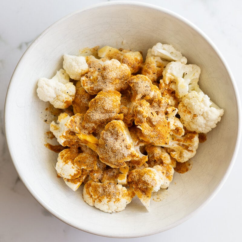 curried cauliflower in a bowl before the spices are mixed on the cauliflower