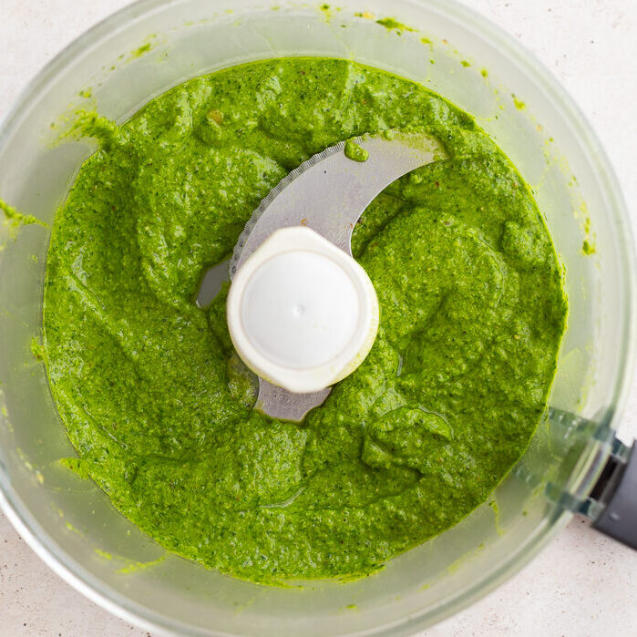 fresh homemade pesto blended up in a food processor base.