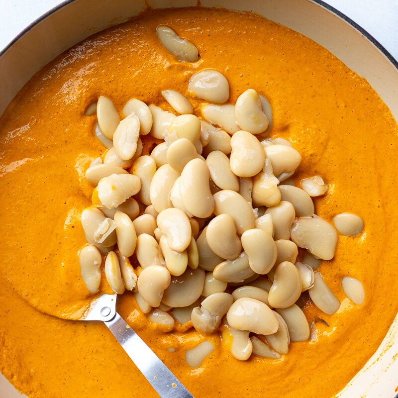 romesco sauce in a skillet with beans poured on top before theyve been stirred in