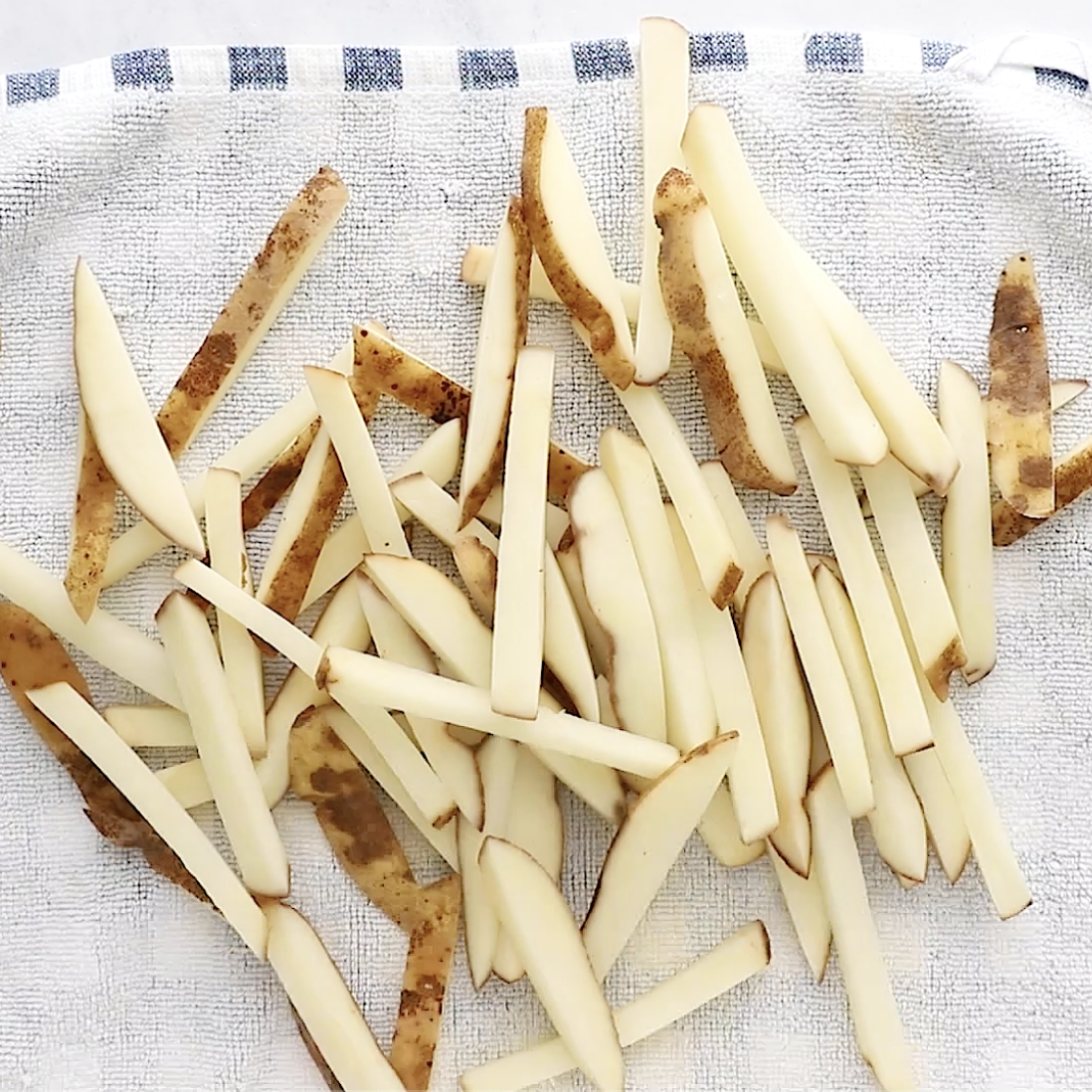 raw potato fries on a towel before being dried off