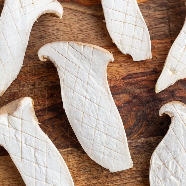 king oyster mushrooms scored on a cutting board