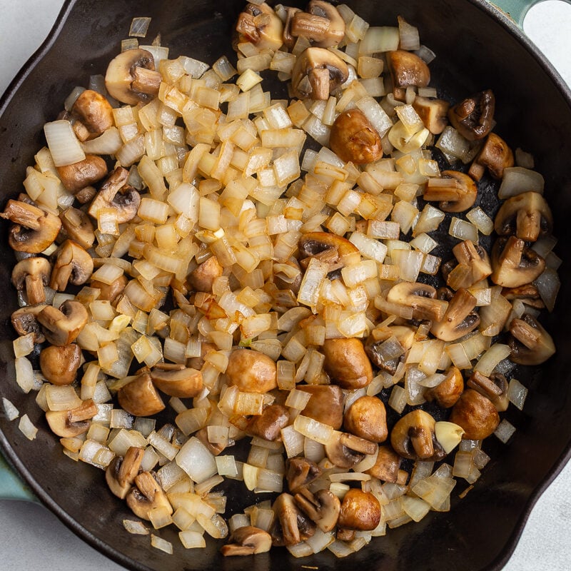 cooked mushrooms and onion in a large cast iron skillet