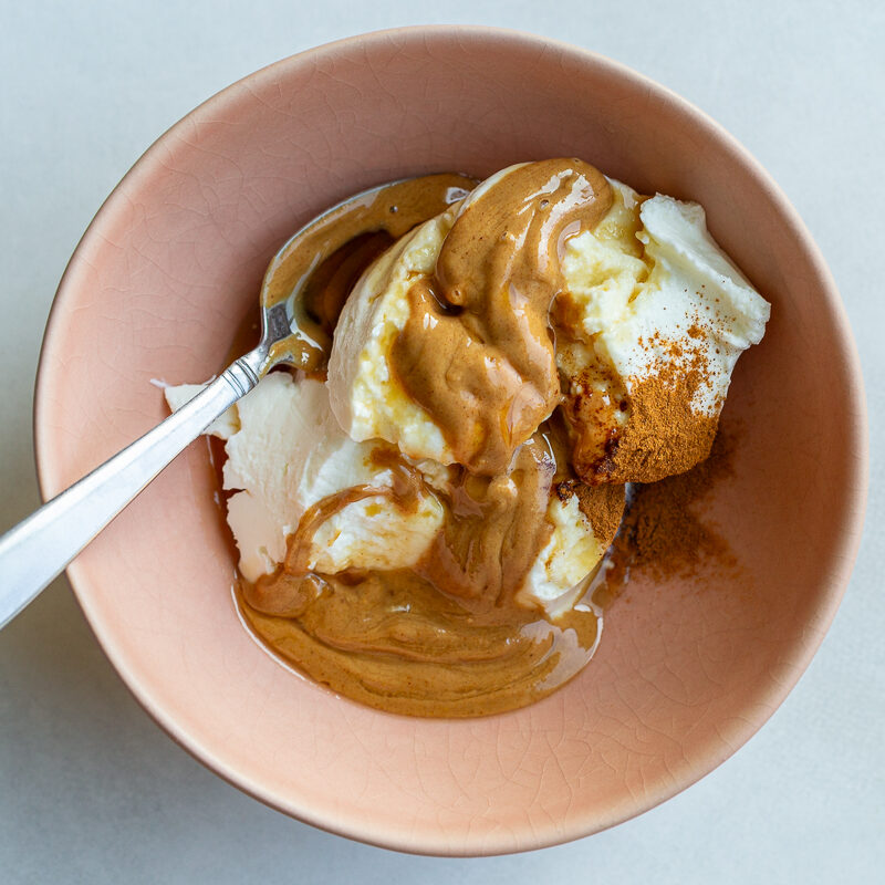 ingredients in a bowl to make fruit dip including yogurt, peanut butter, and cinnamon