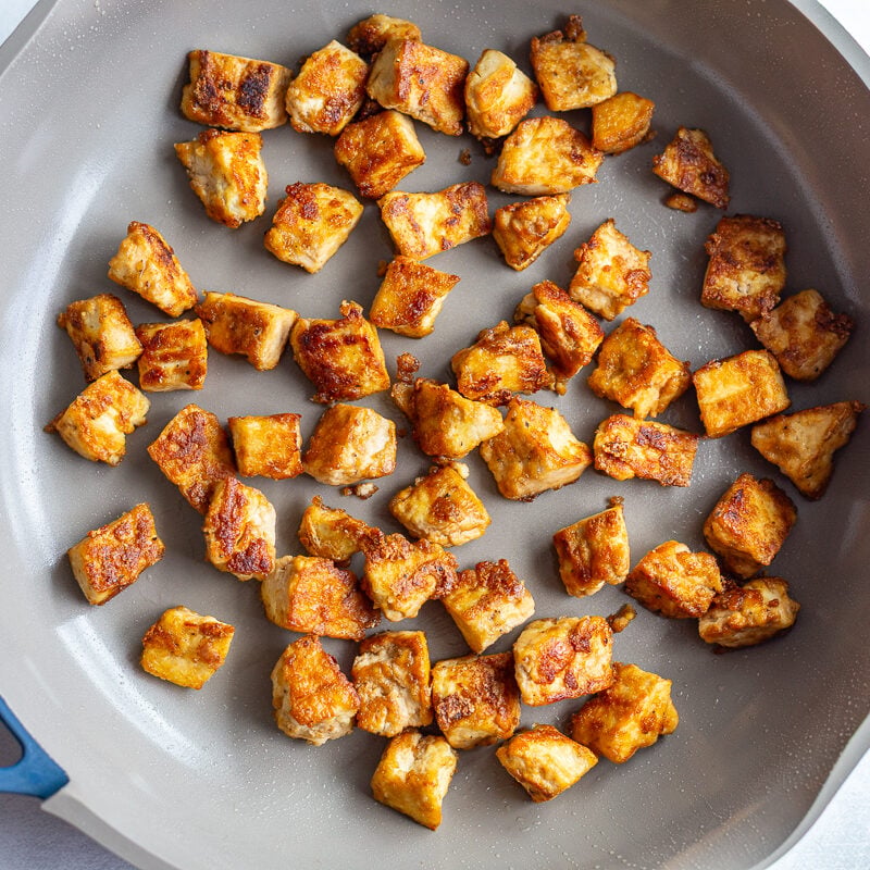 pan fried tofu chunks in a large skillet after they have been cooked