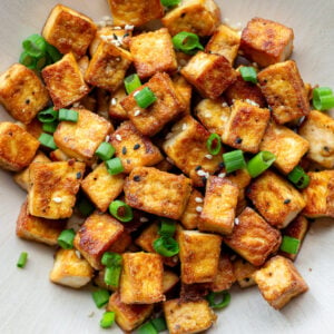 crispy pan fried tofu cubes on a plate with green onion
