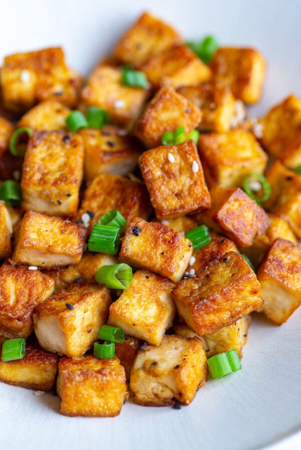 crispy pan fried tofu cubes on a plate with green onion