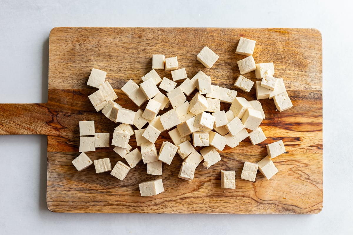 tofu cut into cubes on a wood cutting board