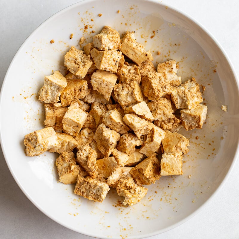 torn pieces of tofu in a large bowl after being tossed with cornstarch and spices