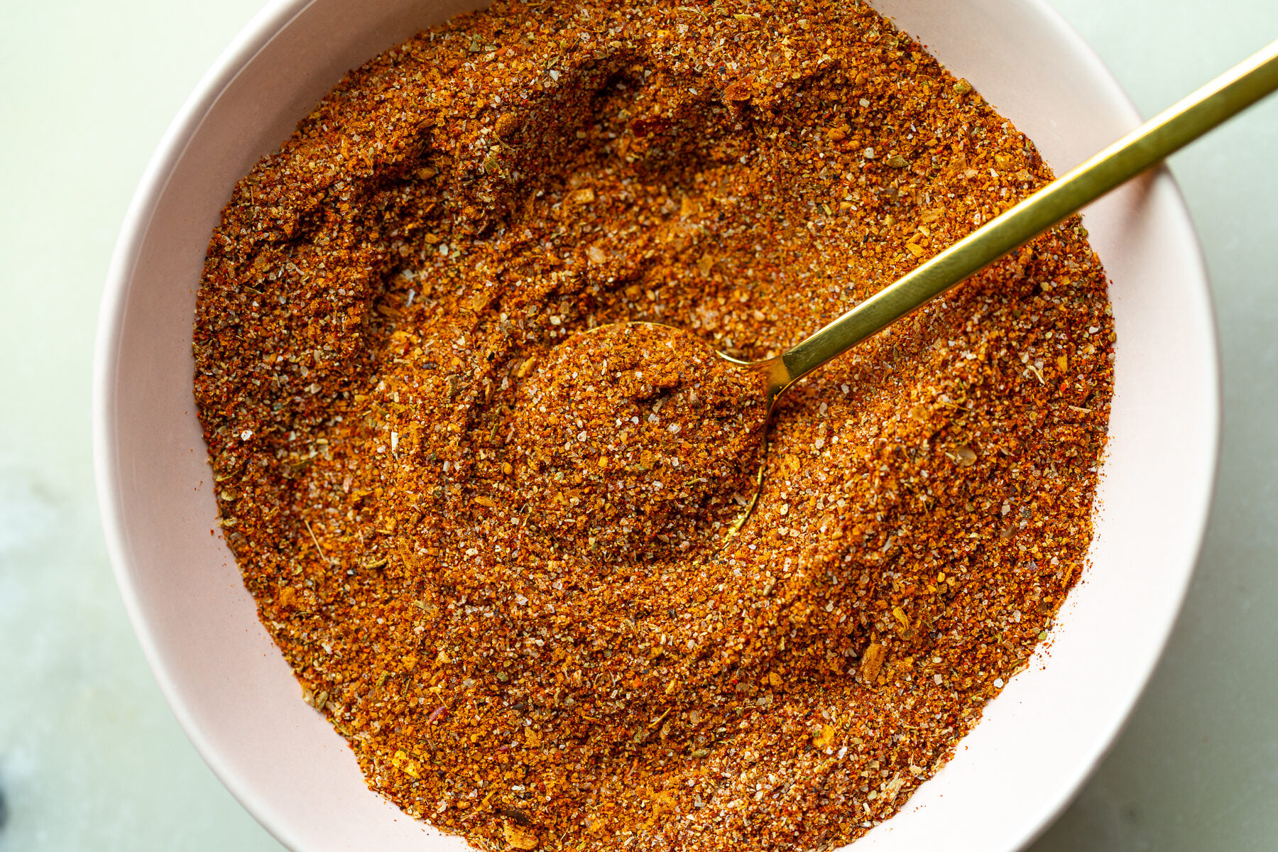 homemade fajita seasoning in a small bow with a gold spoon dipped in it