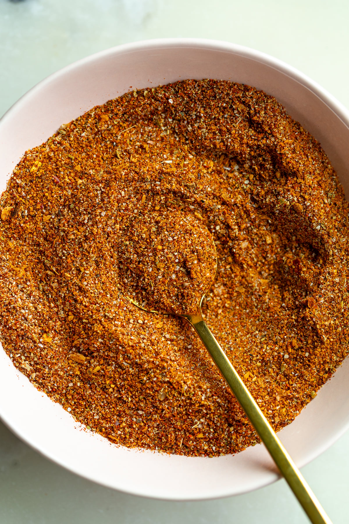homemade fajita seasoning in a small bow with a gold spoon dipped in it