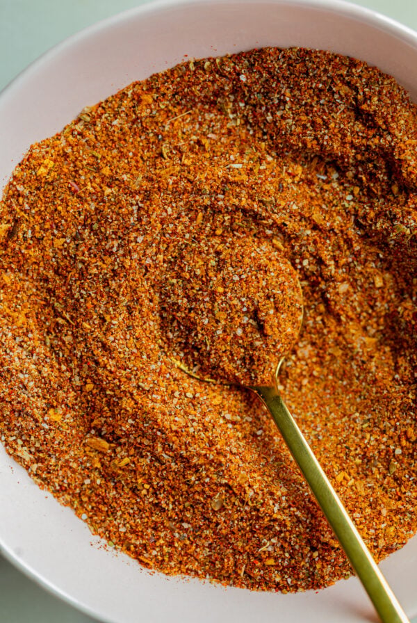 homemade fajita seasoning in a small bow with a gold spoon dipped in it