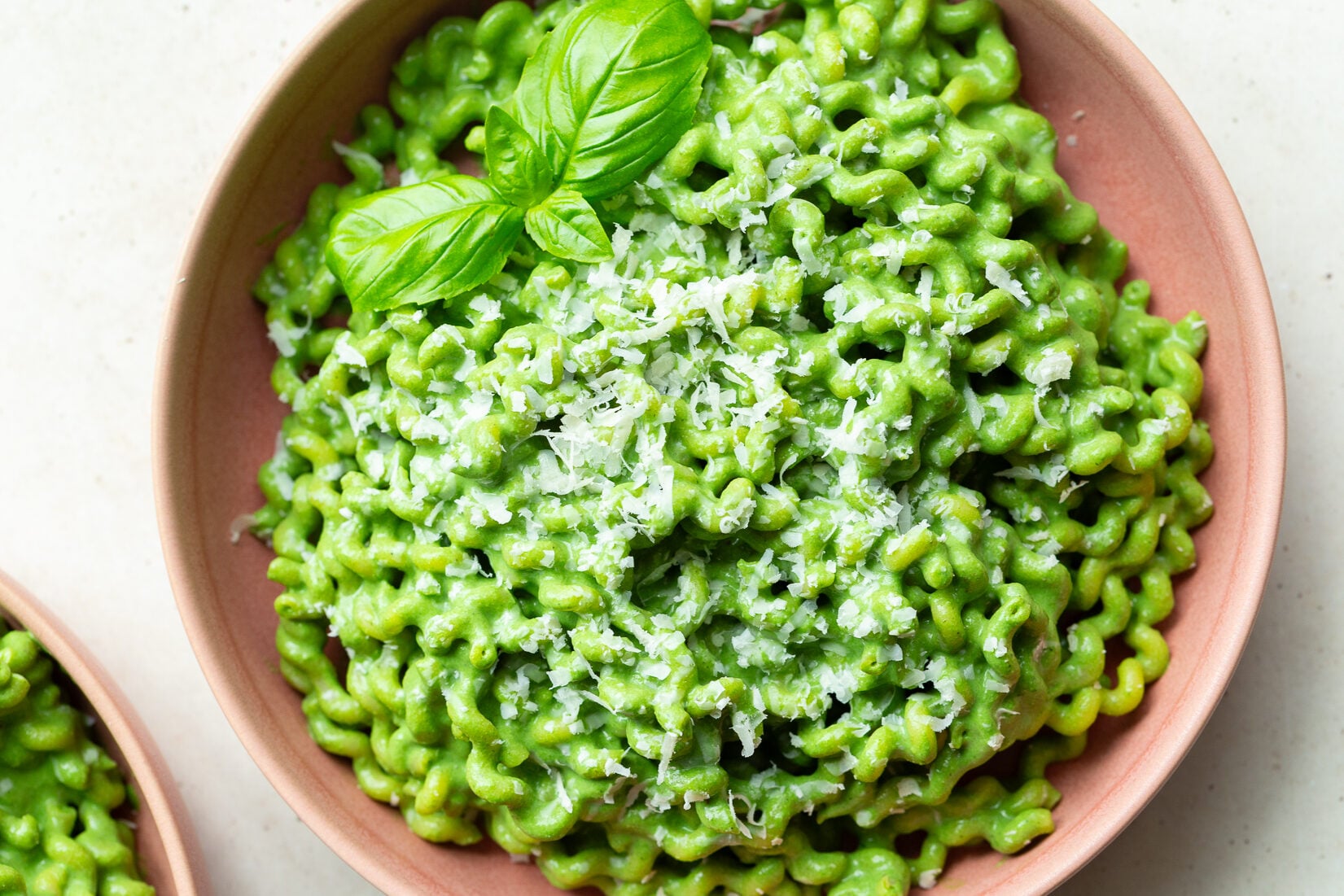 Green pasta garnished with basil leaves.