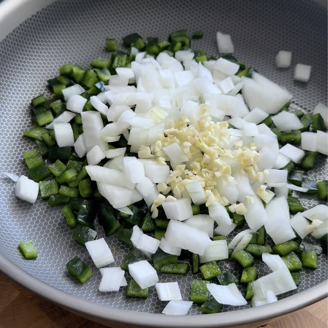 poblano pepper, onion, and garlic cooking in a skillet