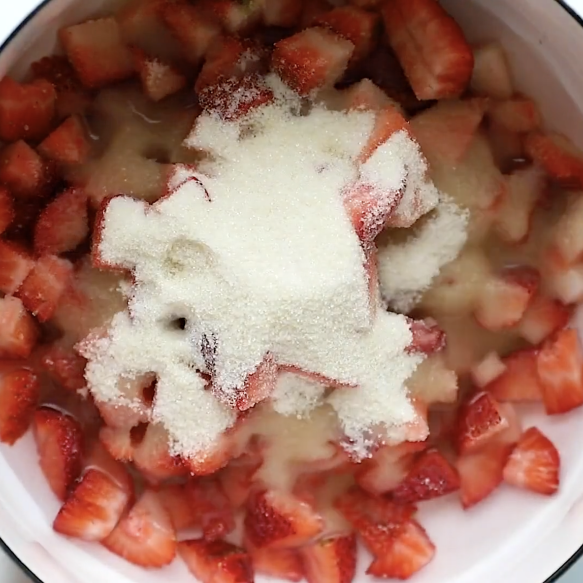 strawberries and sugar in a pot before cooking into strawberry syrup