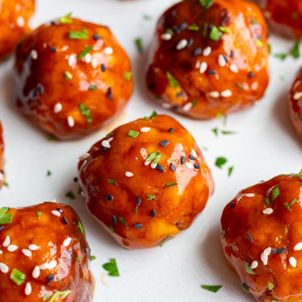 tofu meatballs covered in a sticky sauce and sesame seeds