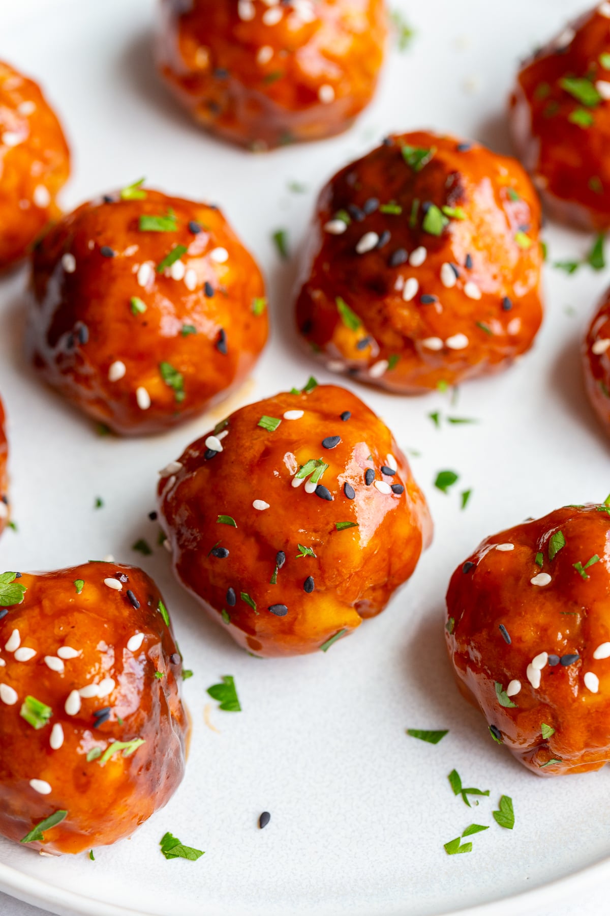 tofu meatballs covered in a sticky sauce and sesame seeds