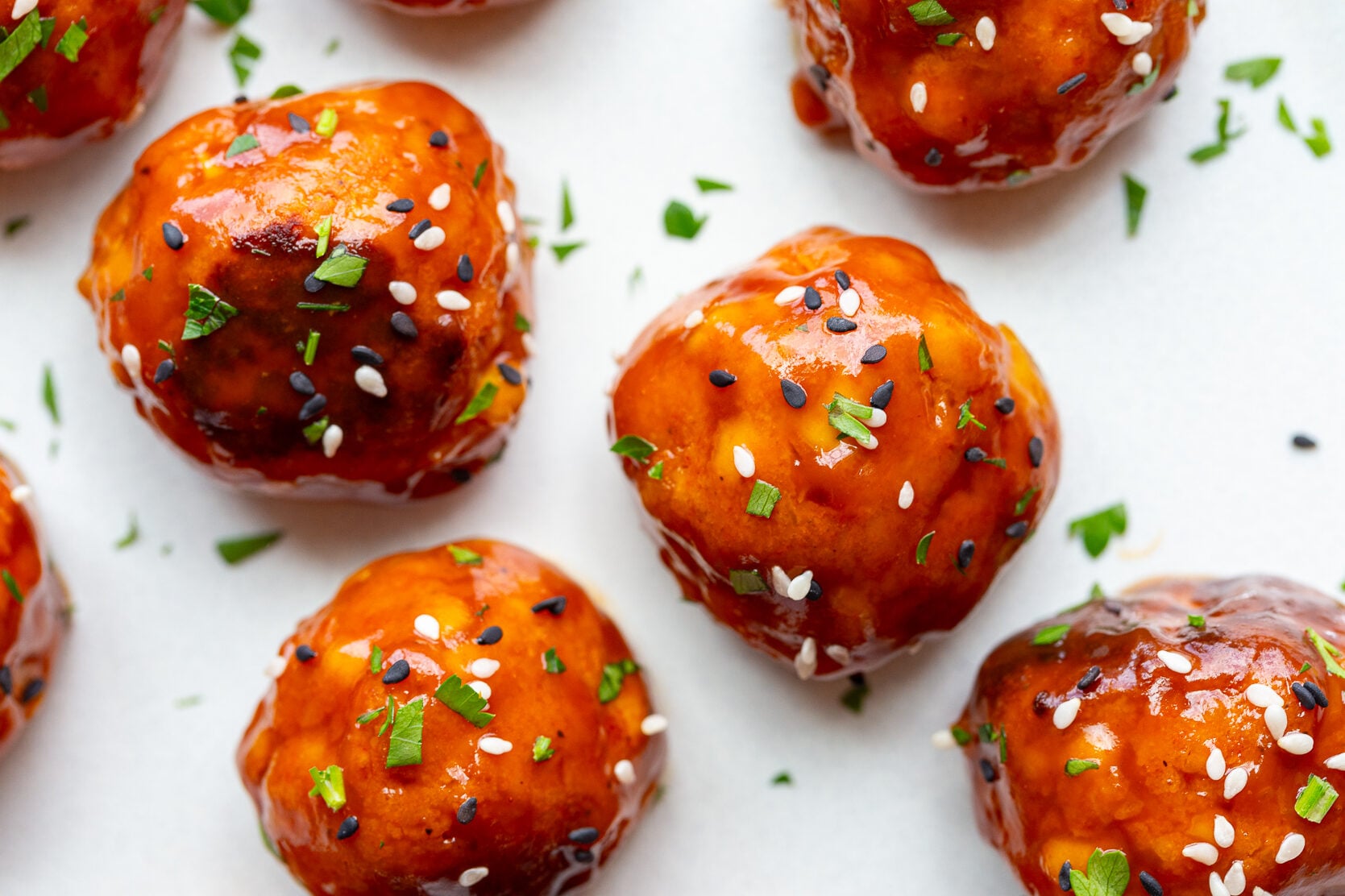 tofu meatballs covered in a sticky sauce and sesame seeds