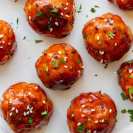tofu meatballs covered in a sticky sauce and sesame seeds