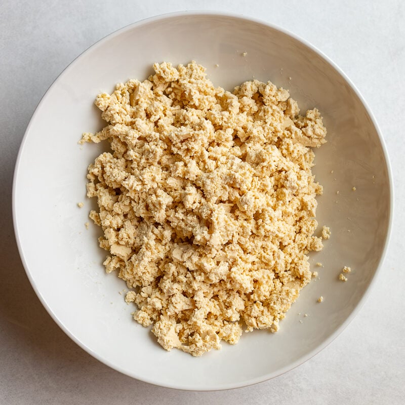 Crumbled tofu in a white bowl before being mixed with seasonings.