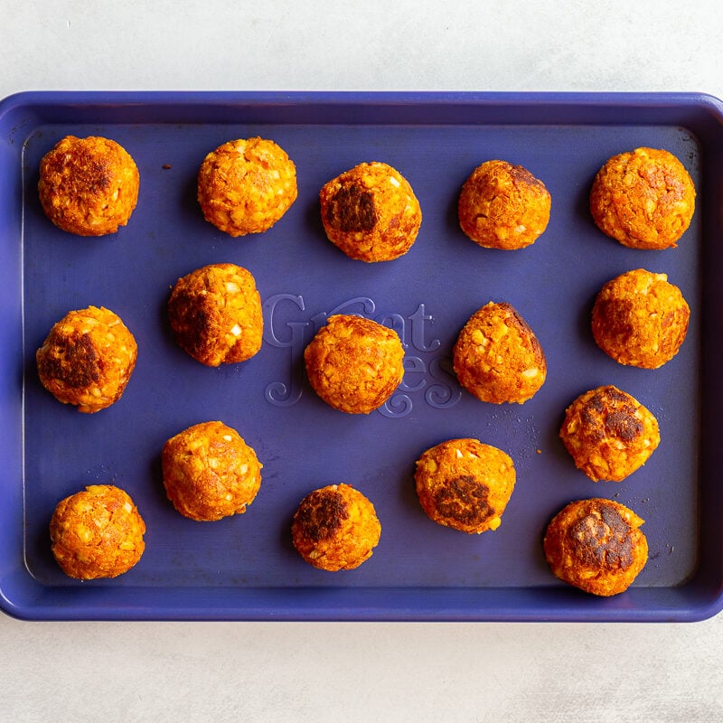 Tofu meatballs on a baking sheet after being baked until golden and firm.