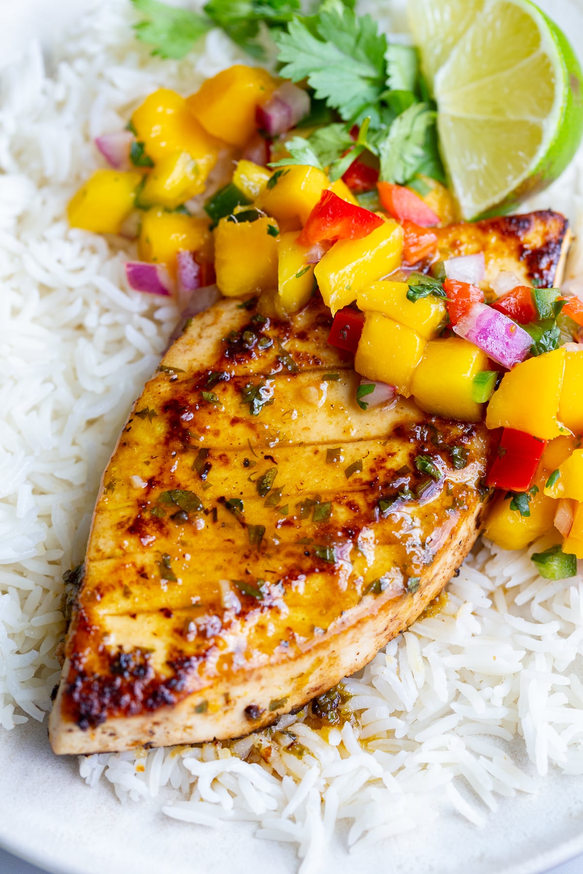 cilantro lime tofu that looks like grilled chicken with a mango salsa on top. all on a bed of rice