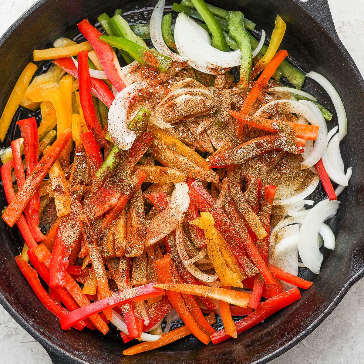Adding vegetables and spices to a skillet.
