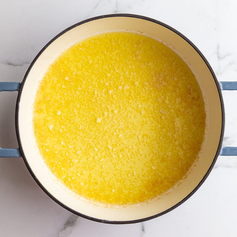 Minced garlic sizzling in melted butter in a large pot until fragrant.